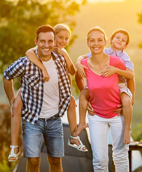 Mutter und Vater tragen ihr schönes Kind auf dem Rücken in der Natur